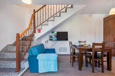 a living room with a dining room table and a staircase at Casa do Palheiro Ribeirinho by Rent-a-key in Porto Moniz