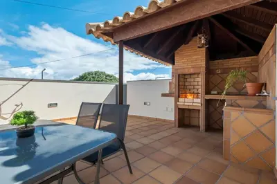 a patio with a blue table and chairs and a grill at Casa do Palheiro Ribeirinho by Rent-a-key in Porto Moniz