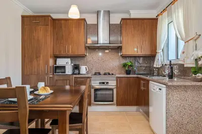 a kitchen with wooden cabinets and a wooden table at Casa do Palheiro Ribeirinho by Rent-a-key in Porto Moniz