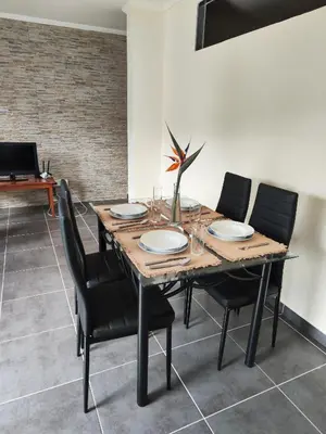 a dining room with a wooden table and black chairs at Quinta' Home in Ribeira da Janela
