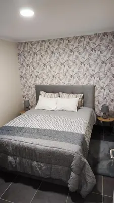 a bedroom with a large bed with a stone wall at Quinta' Home in Ribeira da Janela