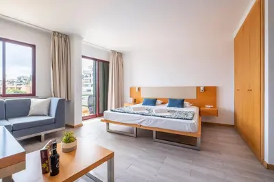 a hotel room with a bed and a couch and a table at Sarah's Apartment by GALMI in Caniço