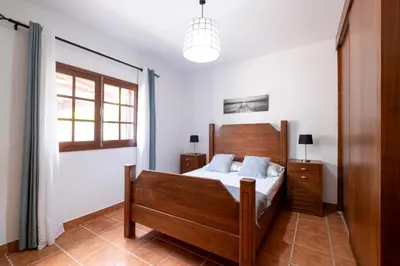 a bedroom with a wooden bed and a window at Casa del Mar I by GALMI in Arco de São Jorge