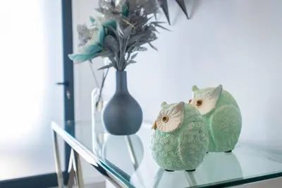two green owls sitting on a glass table with a vase at Villa Otto by GALMI in Campanário