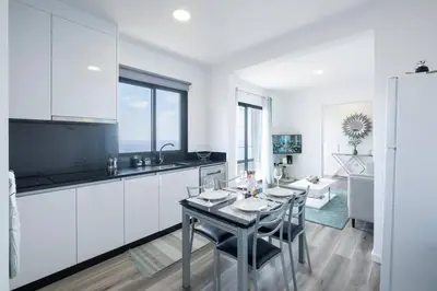 a kitchen with white cabinets and a table and chairs at Villa Otto by GALMI in Campanário