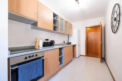 a kitchen with wooden cabinets and a stove top oven at Wings Apartment CE by GALMI in Santa Cruz