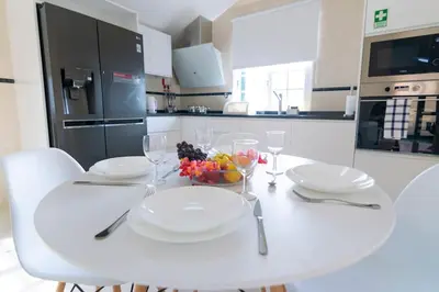 a white dining room table with white plates and glasses at Branco's Apartment by GALMI in Ponta do Sol