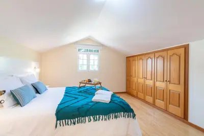 a bedroom with a large white bed and wooden cabinets at Branco's Apartment by GALMI in Ponta do Sol