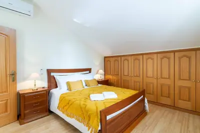 a bedroom with a large bed with a yellow blanket at Branco's Apartment by GALMI in Ponta do Sol