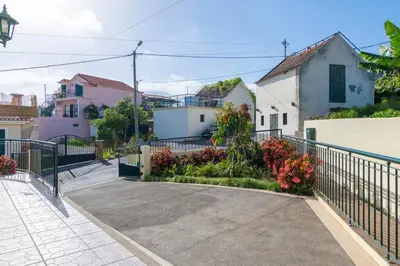 a driveway with a fence and flowers at Branco's Apartment by GALMI in Ponta do Sol