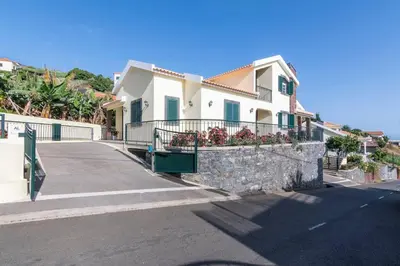 a house with a stone wall next to a street at Branco's Apartment by GALMI in Ponta do Sol