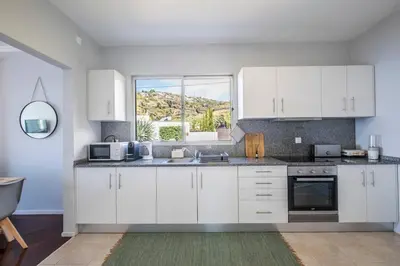 a kitchen with white cabinets and a window at Bernarda's House by GALMI in Ponta do Sol
