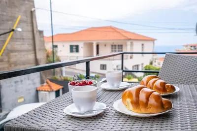 a table with two plates of donuts and two cups of coffee at Alegria's Apartment by GALMI in Calheta