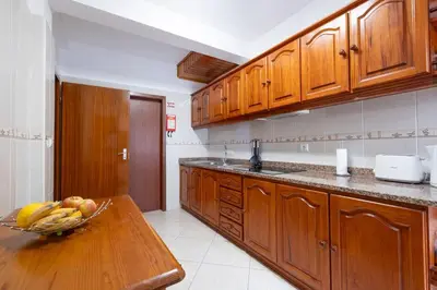 a kitchen with a bowl of fruit on a wooden table at Alegria's Apartment by GALMI in Calheta