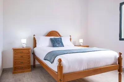 a bedroom with a bed and a nightstand with two lamps at Alegria's Apartment by GALMI in Calheta