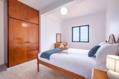 a bedroom with a large white bed with a wooden cabinet at Alegria's Apartment by GALMI in Calheta