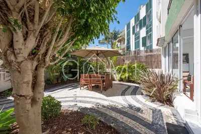 a table with an umbrella next to a building at Stylish Garden Apartment by GALMI in Caniço