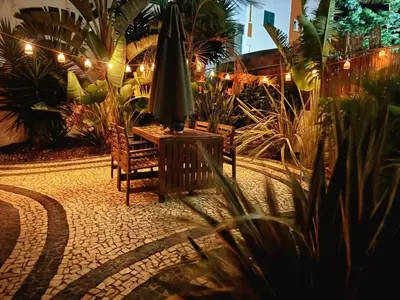 a patio with an umbrella and a bench and plants at Stylish Garden Apartment by GALMI in Caniço