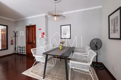a dining room with a black table and white chairs at Stylish Garden Apartment by GALMI in Caniço
