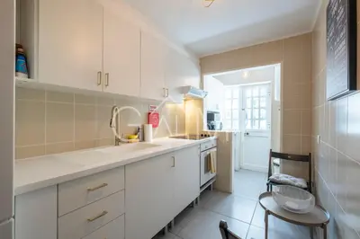 a kitchen with white cabinets and a sink at Stylish Garden Apartment by GALMI in Caniço