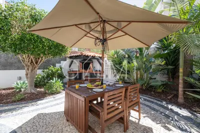 a table with an umbrella on a patio at Stylish Garden Apartment by GALMI in Caniço
