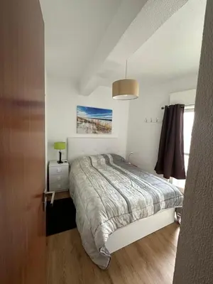 a white bedroom with a bed and a window at Sun Beach Apartment in Machico