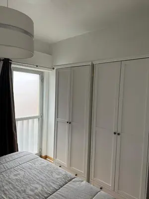 a bedroom with white cabinets and a bed and a window at Sun Beach Apartment in Machico