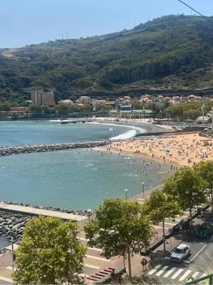 a beach with a bunch of people in the water at Sun Beach Apartment in Machico