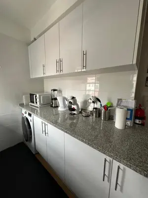 a kitchen with white cabinets and a washing machine at Sun Beach Apartment in Machico