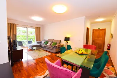 a living room with a table and colorful chairs at Tranquility Apartment in Caniço