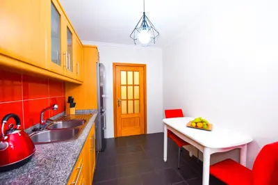 a kitchen with a sink and a red chair at Tranquility Apartment in Caniço