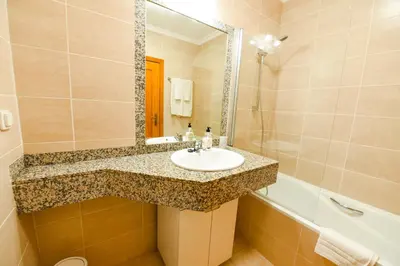 a bathroom with a sink and a mirror and a tub at Tranquility Apartment in Caniço