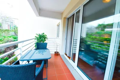 a balcony with a blue table and chairs and a window at Tranquility Apartment in Caniço