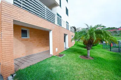a brick building with a palm tree next to a building at Tranquility Apartment in Caniço