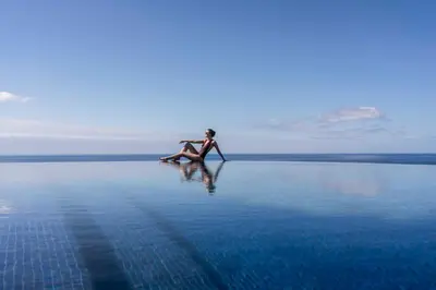 a woman sitting on a rock in the middle of the water at The Reserve - within Savoy Palace - The Leading Hotels of the World in Funchal