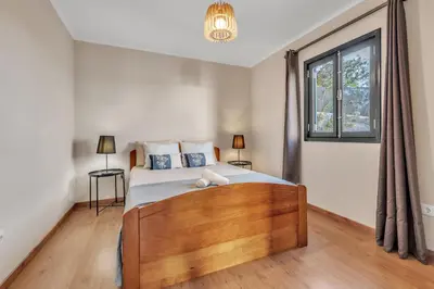 a bedroom with a bed and a large window at Chalé do Areeiro in Funchal