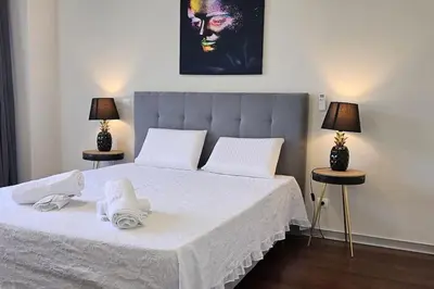 a bedroom with a bed with white sheets and two lamps at Ponte de Estrelas Plaza by Rentallido in Funchal