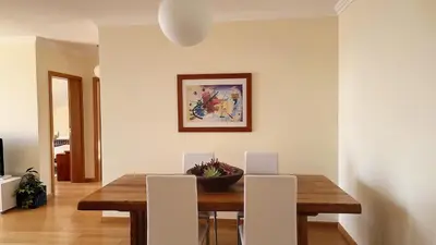 a dining room with a wooden table and white chairs at Lucy Sweet Home by LovelyStay in Caniço