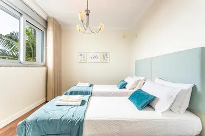 two beds in a bedroom with a chandelier at Moradia Vista Atlântico in Funchal