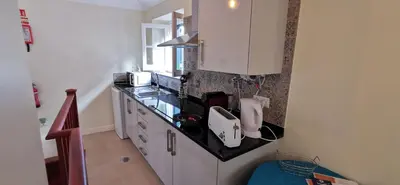 a kitchen with white cabinets and a black counter top at Franciscus 2c in Funchal