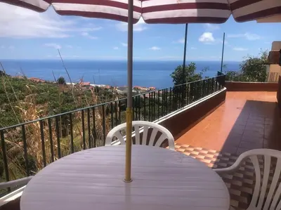 a white table with an umbrella on a balcony at Casa Vista Mar -2 bedrooms,fantastic Seaview in Estreito da Calheta