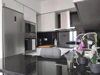 a kitchen with white cabinets and a counter with flowers at Arrifes View 2 Funchal by Rentallido in Funchal