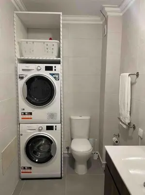 a bathroom with a toilet and a washer and dryer at Elm Apartament in Sagres