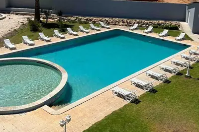 a large swimming pool with chairs and a swimming pool at Elm Apartament in Sagres