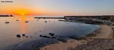 a beach with a pier and boats in the water at Elm Apartament in Sagres