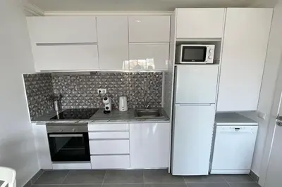 a kitchen with white cabinets and a white refrigerator at Elm Apartament in Sagres