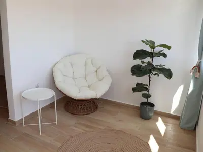 a white chair sitting in a room with a plant at Casa Vento Budens in Budens