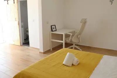 a bedroom with a bed with a desk and a chair at Casa Vento Budens in Budens