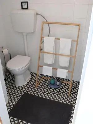 a bathroom with a toilet and a shelf with towels at Casa Vento Budens in Budens