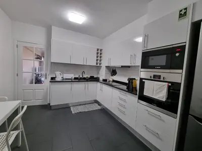 a white kitchen with white cabinets and black appliances at Olimpia Gardens View by Rentallido in Funchal